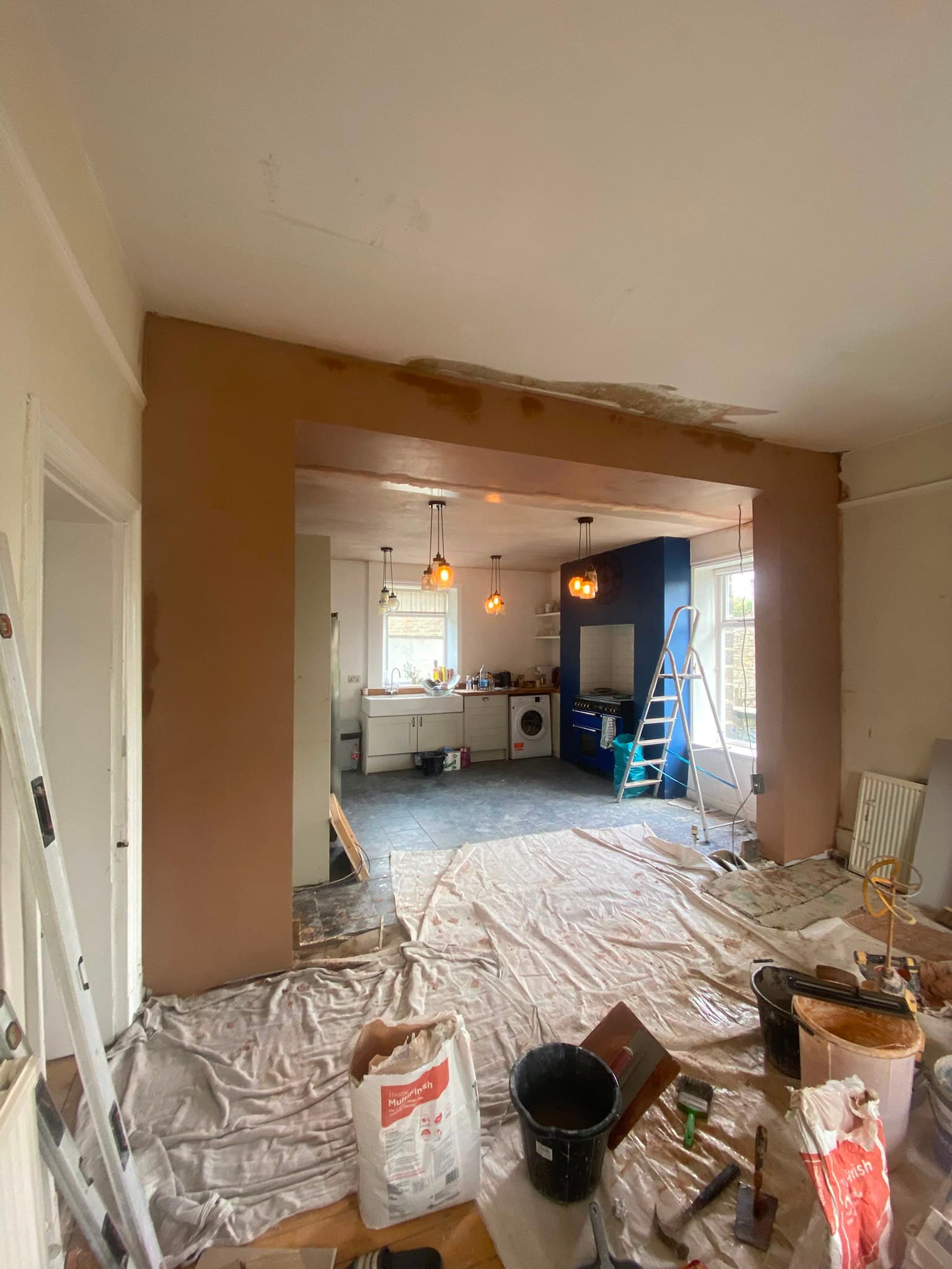 A kitchen extension opening freshly skimmed, dust sheets down and tools on the floor
