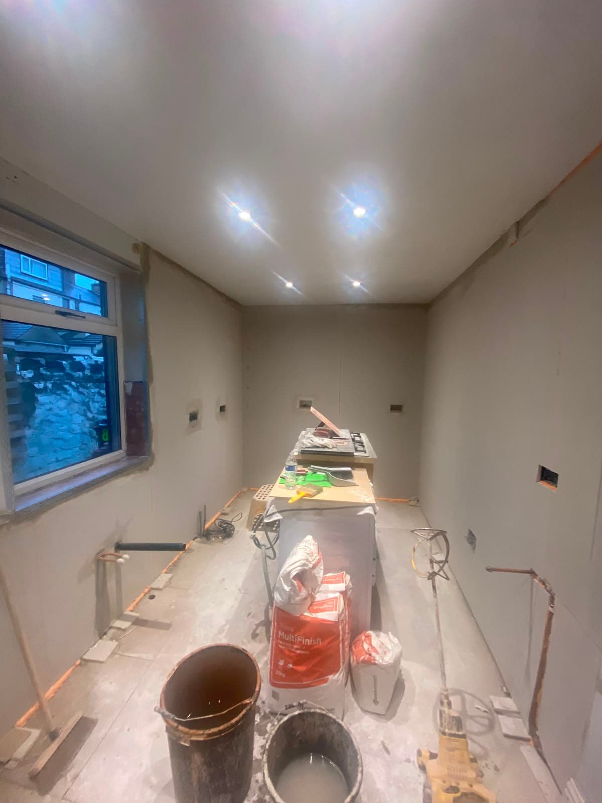 A freshly plasterboarded room set up with a mixing station and bags of Multi Finish