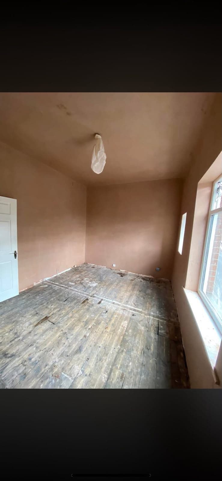 An empty freshly skimmed bedroom with a white door and a bay window