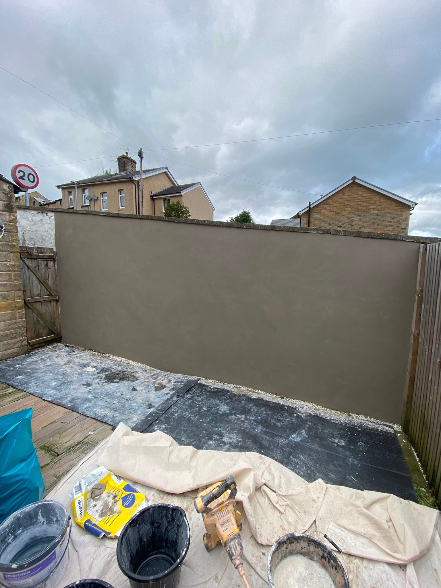 A close-up of a finished rendered garden wall with a bag of Weber render on the sheeting