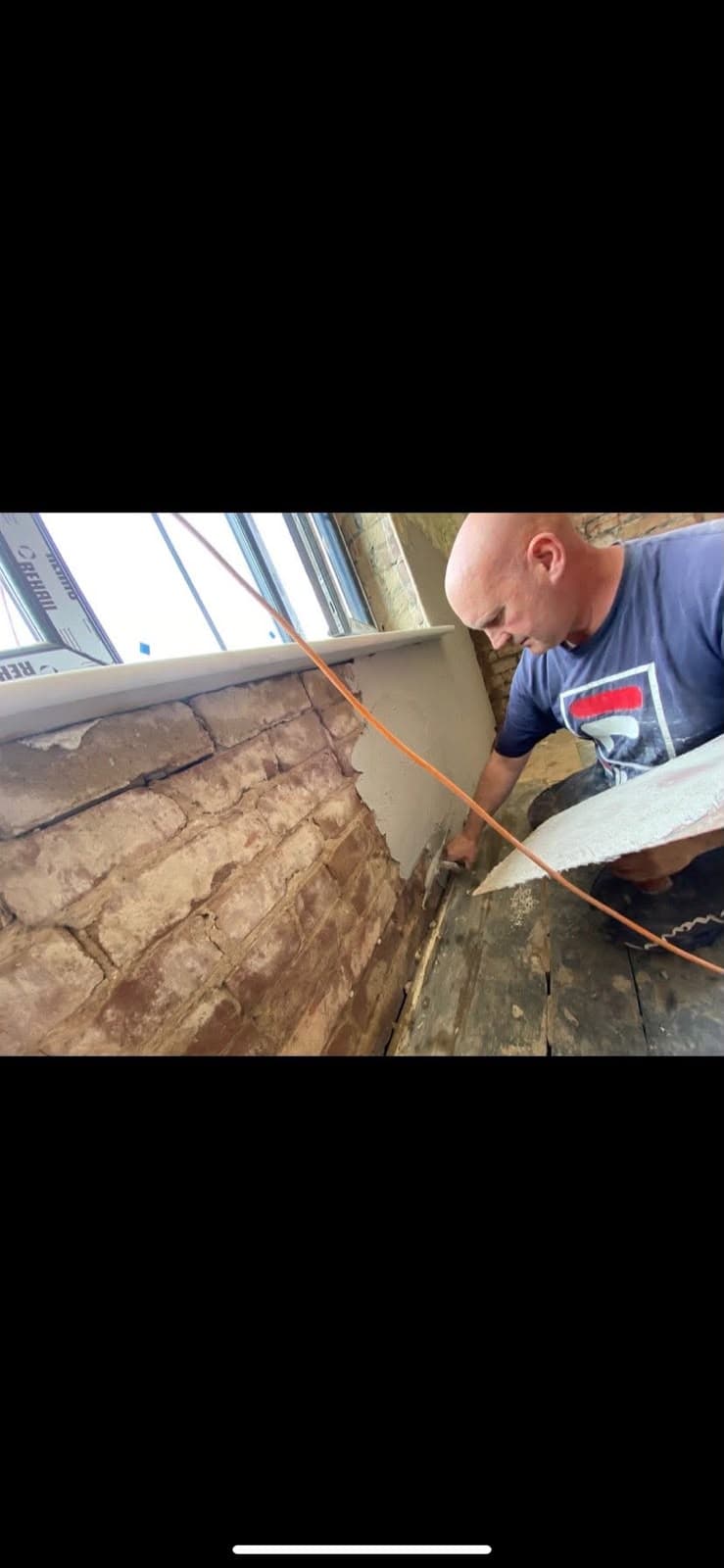 A plasterer patching an exposed brick wall ready for boarding